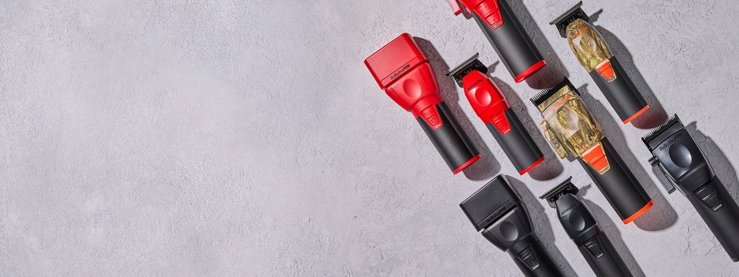collection of barber tools in red, camo, and black colors on a grey concrete background.