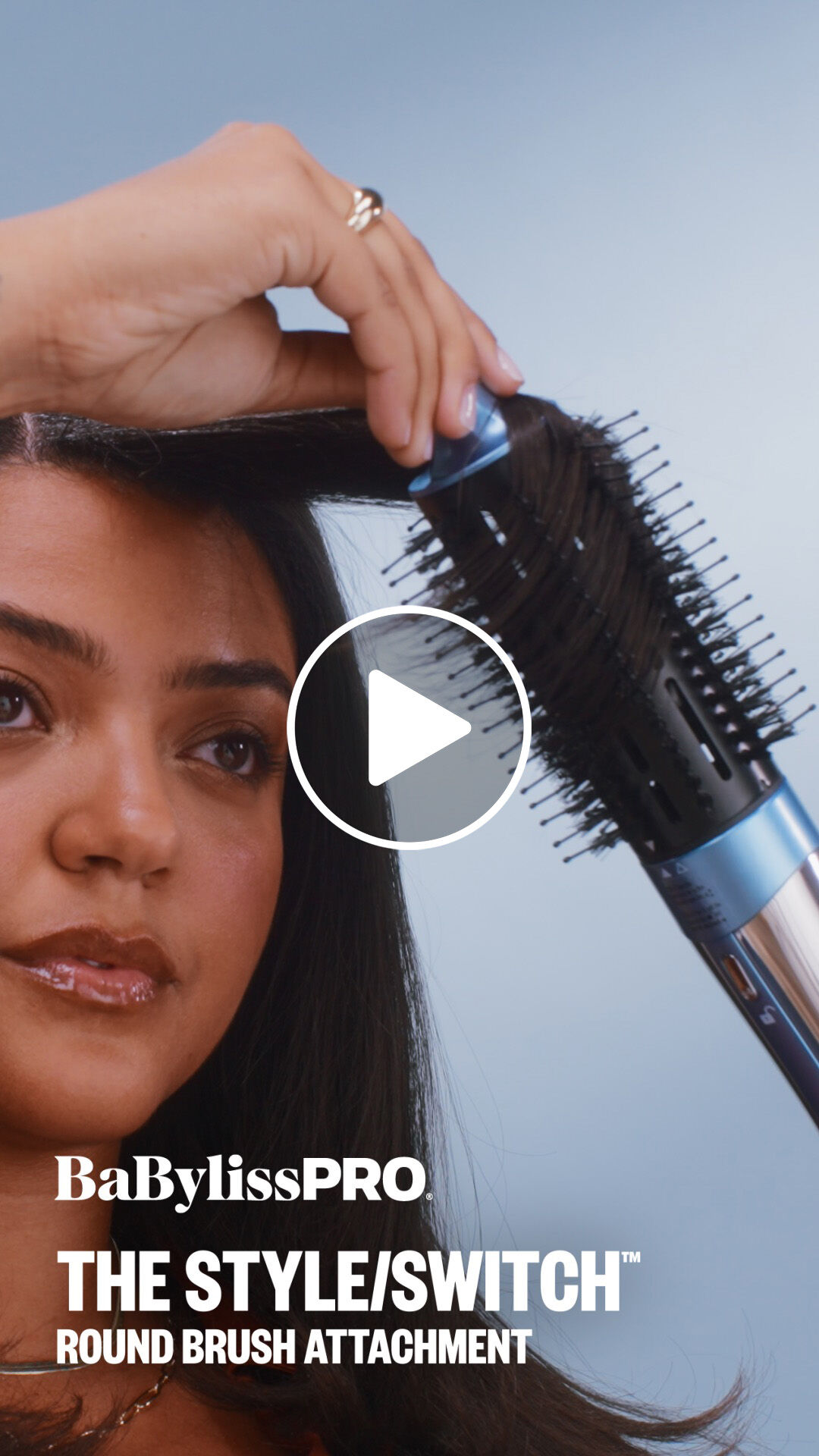 A woman with dark brown hair using a BaBylissPRO round brush attachment to add soft curls to her hair with the style switch multi styler hair tool