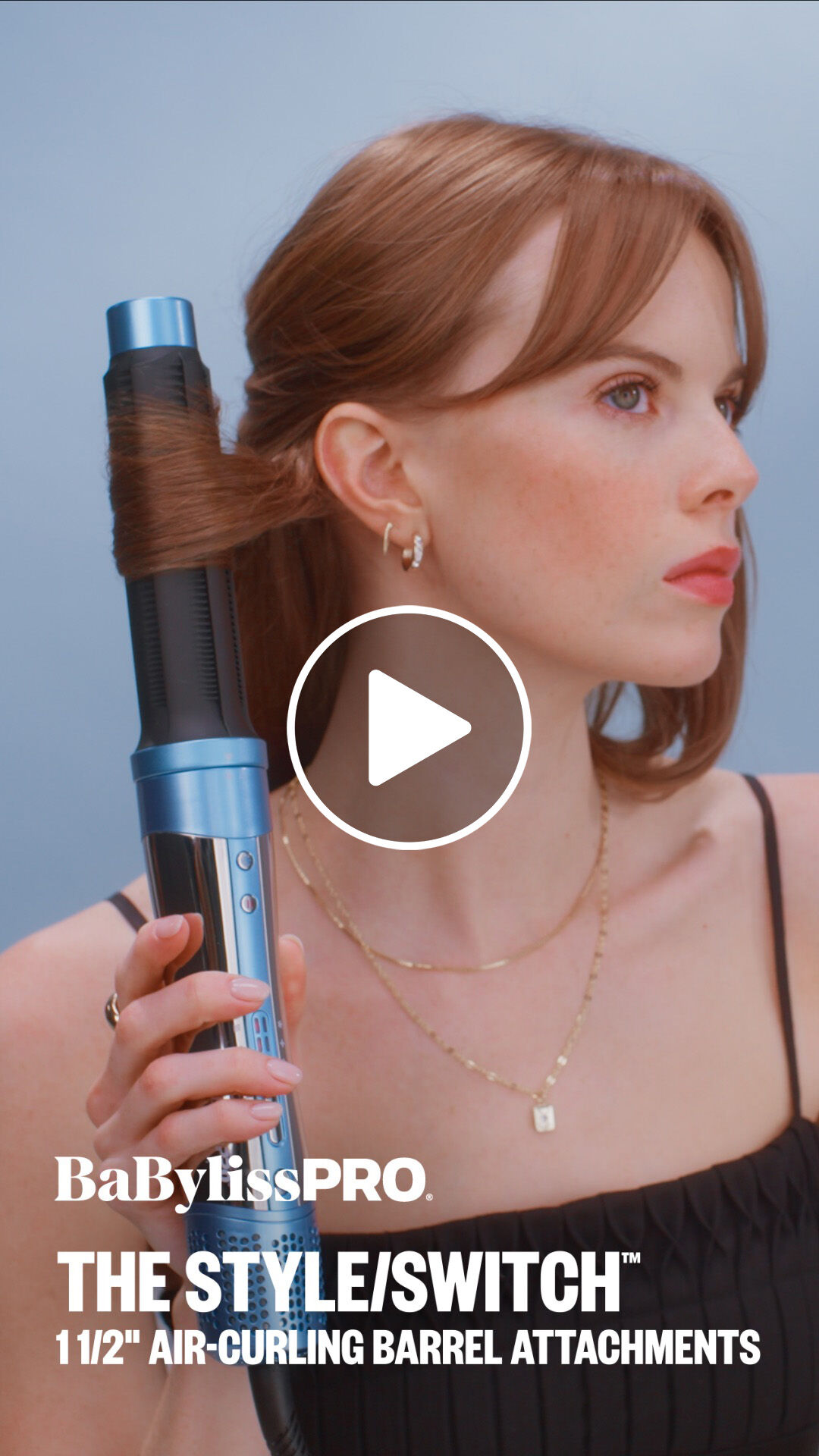 A woman with light red hair using a BaBylissPRO one-and-a-half-inch air curling barrel attachment to style her hair with her style switch multi styler hair tool