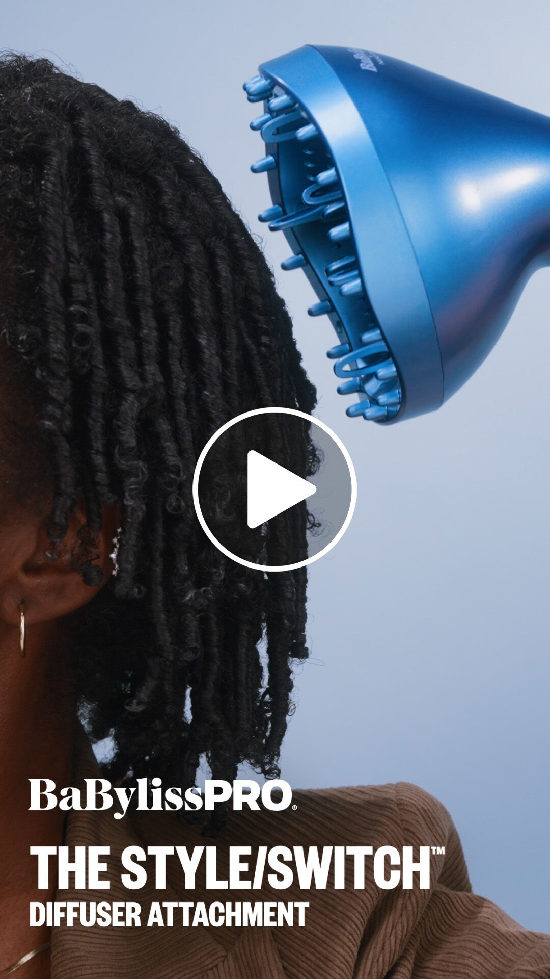 A woman with black coily hair using a BaBylissPRO diffuser attachment to enhance natural curls and waves while minimizing frizz with the style switch multi styler hair tool