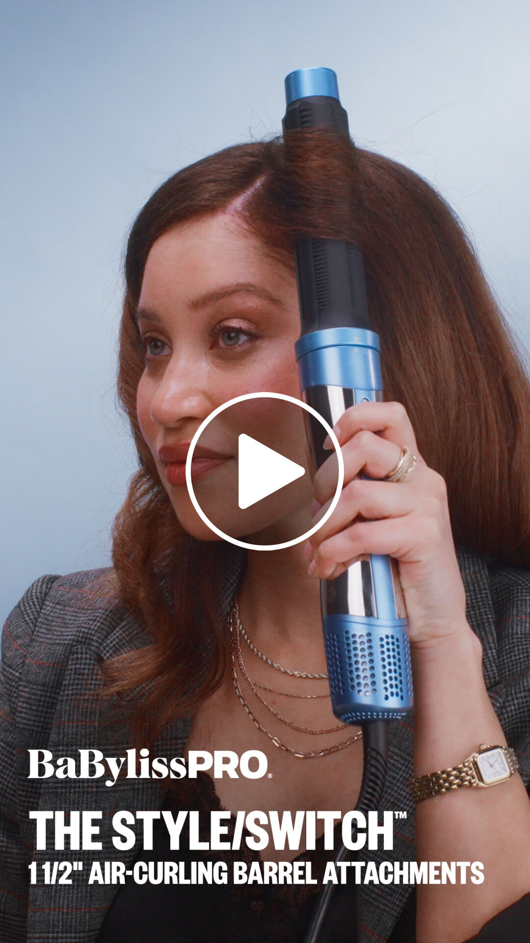 A woman with brown hair using a BaBylissPRO one-and-a-half-inch air curling barrel attachment to style her hair with the style switch multi styler hair tool