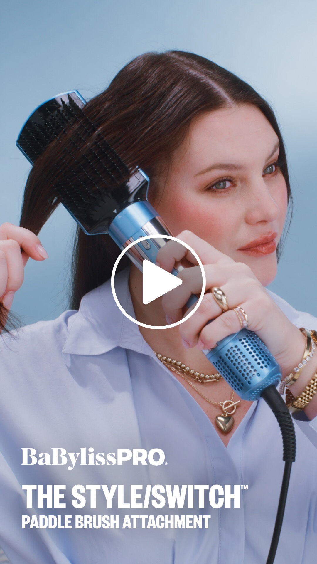 A woman with dark brown hair using a BaBylissPRO paddle brush attachment to brush through her hair with the style switch multi styler hair tool